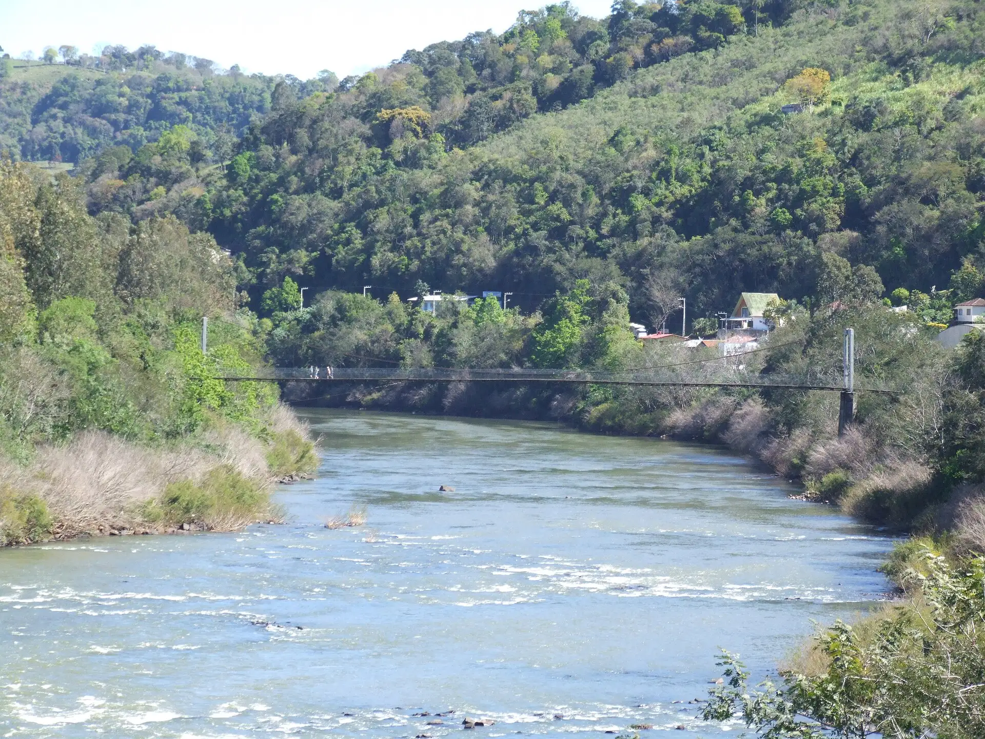 Ponte pênsil sobre o Rio do Peixe entre morros cobertos de mata